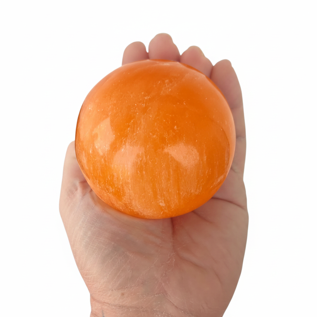 Esfera selenita naranja vibrante en mano